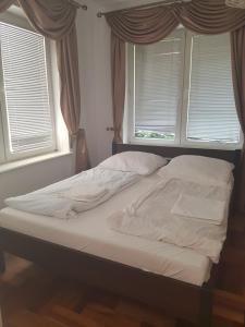 an unmade bed in a bedroom with two windows at Willa Aqua -parking included in the price in Świnoujście