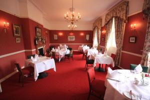 um restaurante com mesas e cadeiras brancas e um lustre em Worsley Arms Hotel em Hovingham