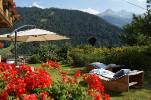 une chaise et un parasol dans un jardin fleuri dans l'établissement Ferienhaus "Plankschneider", à Matrei in Osttirol