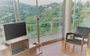 sala de estar con TV, silla y ventana grande en Casa de ls Cristales, en Bemposta