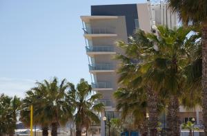 a building with palm trees in front of it at Water's Edge Hotel in Birżebbuġa