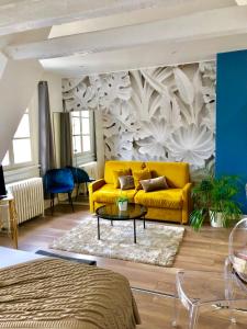 a yellow couch in a living room with a wall at LIFE RENAISSANCE - New Concept - Place Kléber in Strasbourg