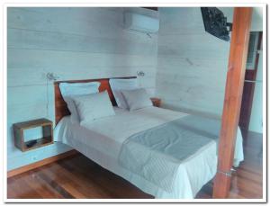 sypialnia z białym łóżkiem z drewnianym zagłówkiem w obiekcie Quenetier w mieście Saint-François