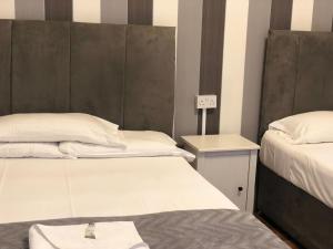 a room with two beds and a nightstand with a bed sidx sidx at The Crystal Lodge Hotel in Croydon
