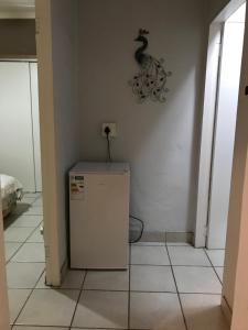 a room with a refrigerator and a clock on the wall at Ian and Pam's Flatlet in Empangeni