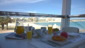 a table with a plate of food and two glasses of orange juice at Water's Edge Hotel in Birżebbuġa