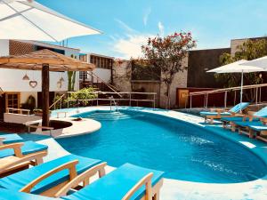 a swimming pool with blue chairs and umbrellas at Hotel Villa Jazmin in Ica