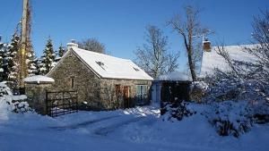 um pequeno edifício de pedra com neve no telhado em The Barn at Pink Cottage em Crossgar