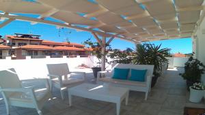 a patio with chairs and tables and a white umbrella at Alkyonari By Maria in Ammouliani