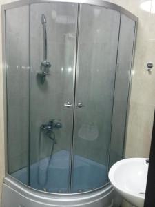 a shower with a glass door next to a sink at View of the Tower of Alphabet in Batumi