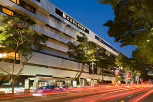 ein Auto, das an einem Gebäude an einer Stadtstraße vorbeifährt in der Unterkunft Concorde Hotel Singapore in Singapur