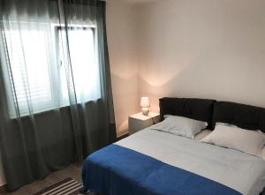 a bedroom with a bed with a blue blanket and a window at Punta Preko Apartments in Preko