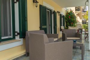 a patio with chairs and tables and green shutters at Dionos Villa in Asos