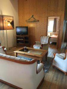 ein Wohnzimmer mit weißen Möbeln und einem TV in der Unterkunft Gästehaus Zur Linde in Otterndorf