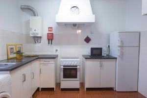 uma cozinha com armários brancos e um frigorífico branco em Casa Caió em Ribeira Grande