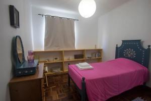 リベイラ・グランデにあるCasa Caióのピンクベッド1台と鏡付きのベッドルーム1室