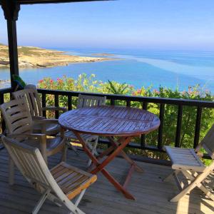 a table and chairs on a deck with a view of the ocean at ZAMBAK Holiday Village in Ayios Yeoryios