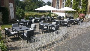 un grupo de mesas y sillas con sombrillas blancas en Hotel Schloss Wilkinghege, en Münster