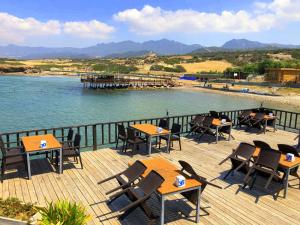 a deck with tables and chairs next to a body of water at ZAMBAK Holiday Village in Ayios Yeoryios