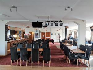 un comedor con mesas y sillas y un bar en The Cliff Top Inn, en Bacton