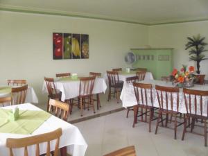 un comedor con mesas blancas y sillas de madera en Pousada Barra Mares, en Mucuri