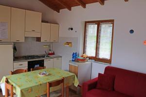 eine Küche mit einem Tisch und einem roten Sofa in der Unterkunft Casa al Lago Trentuno B in Zenna