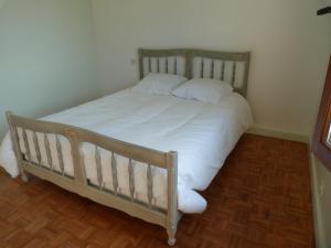 a bed with white sheets and pillows in a room at Jolie maison de campagne in Lainsecq