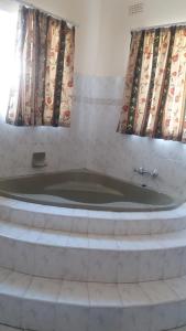 a bath tub in a room with two windows at Tshulu Tsha Nabe B&B in Bulawayo