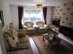 ein Wohnzimmer mit einem Sofa, Stühlen und einem TV in der Unterkunft The Lookout, Glenarm in Glenarm