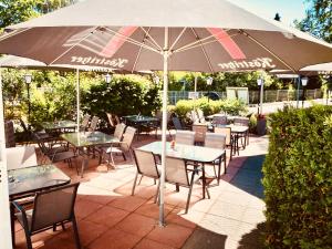 a patio with tables and chairs and an umbrella at Hotel Villa Fröhlich in Baabe