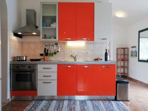 una cucina con armadi rossi e lavandino di Sunny Blue Apartament a Nerezine (Neresine)