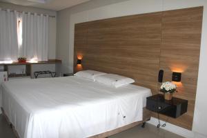 a bedroom with a white bed with a wooden headboard at Chalés Saint Germain in Florianópolis