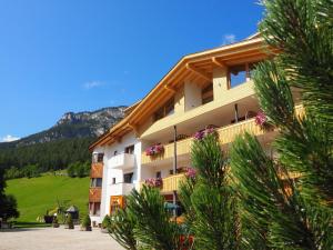 a building with flowers on the balconies with mountains in the background at Pension Rungg in Badia