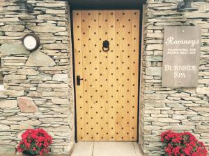 a wooden door in a stone wall with two red flowers at Lakes Hotel & Spa Apartments in Windermere