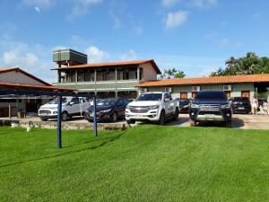 a parking lot with cars parked in front of a building at Pousada Ipê in Salinópolis