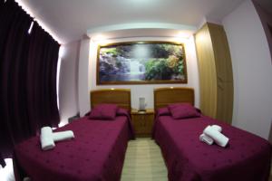 two beds in a room with purple sheets at Pension Pardellas in Palas de Rei