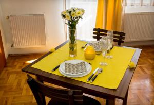 a dining table with a yellow table cloth and a vase of flowers at Anthony in Niš