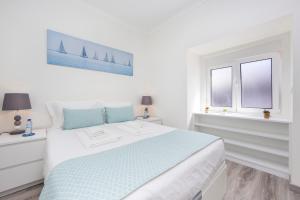 a white bedroom with a bed and two windows at FishermenApartments - Casa do Espargal in Paço de Arcos