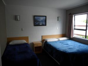 Habitación de hotel con 2 camas y ventana en Loredo Motel, en Kaitaia