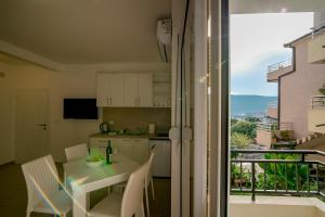 a kitchen with a table and chairs and a balcony at SunnyApartments in Herceg-Novi