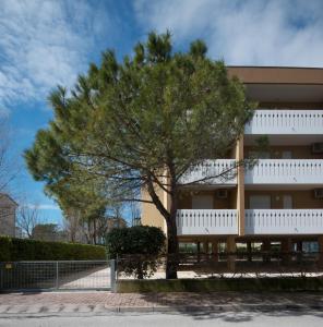 un edificio con un árbol delante de él en Condominio Lavinia, en Bibione