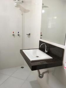 a white bathroom with a sink and a mirror at Hotel Glória Barbacena in Barbacena