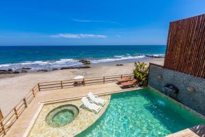 a swimming pool with chairs and a beach at Canoas Lofts in Canoas De Punta Sal