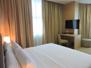 a hotel room with a bed and a desk with a television at Hotel N°5 in Kota Kinabalu