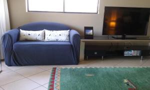 a blue couch in a living room with a flat screen tv at oceanview 6 with rooftop terrace & spa in Nambucca Heads