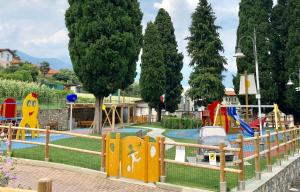 un parque infantil con tobogán en un parque con árboles en Gabry’s Home, en Pianello Del Lario