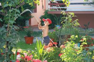 Un ragazzo che gioca con un tubo in giardino di Le Jardin de Temeni a Aigio
