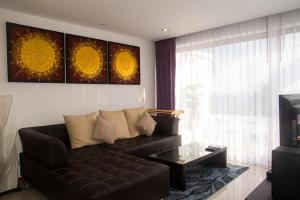 a living room with a black leather couch and a television at Tropical Sea View Residence in Lamai