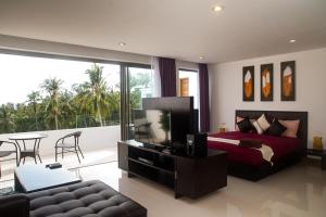 a bedroom with a bed and a tv and a balcony at Tropical Sea View Residence in Lamai