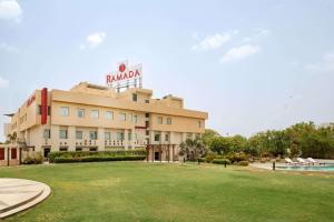 a hotel with a lawn in front of a building at Ramada Ajmer in Kishangarh